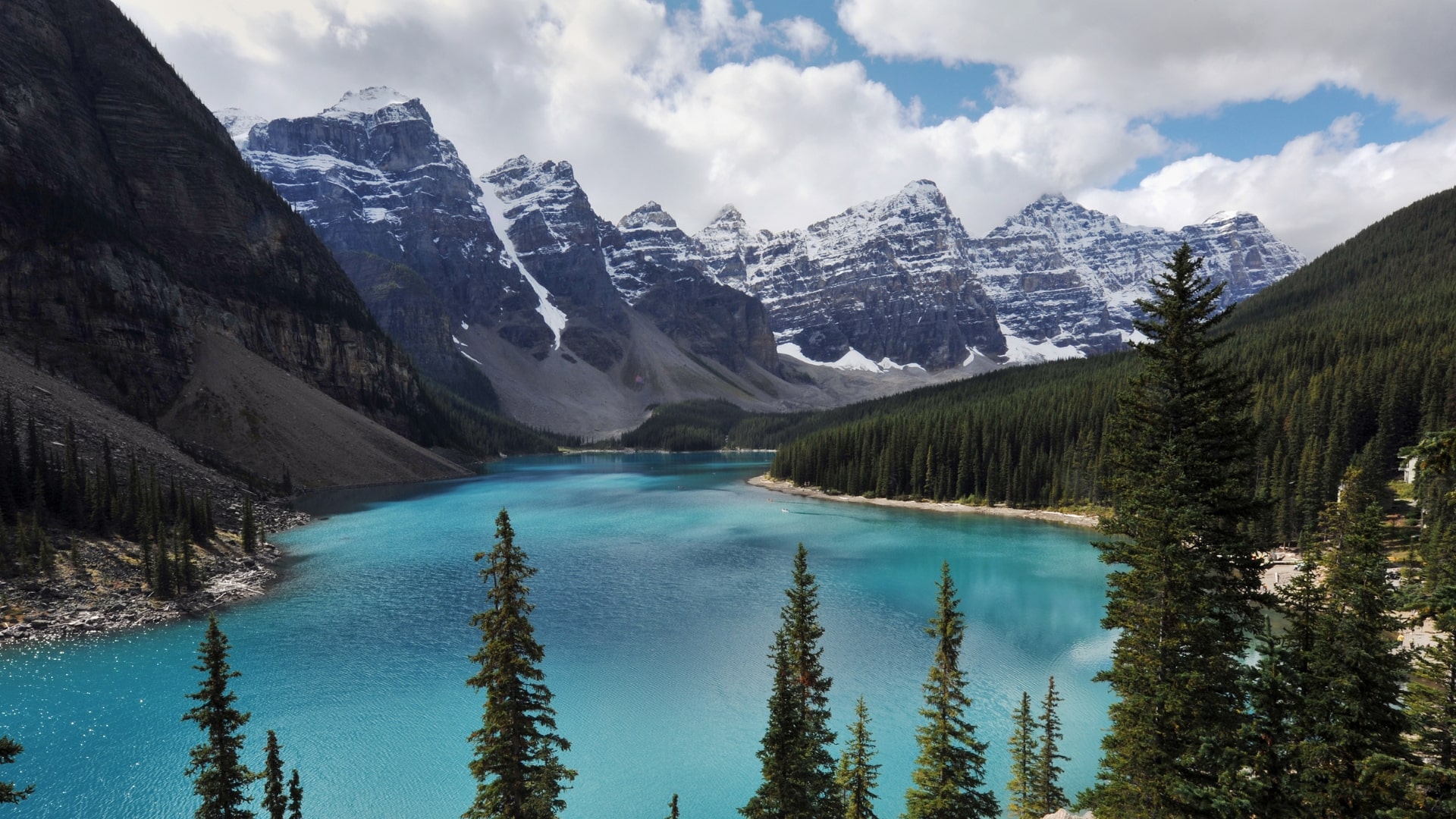 Scenic turquoise lake with pine forest and snow-capped mountains in Banff National Park.