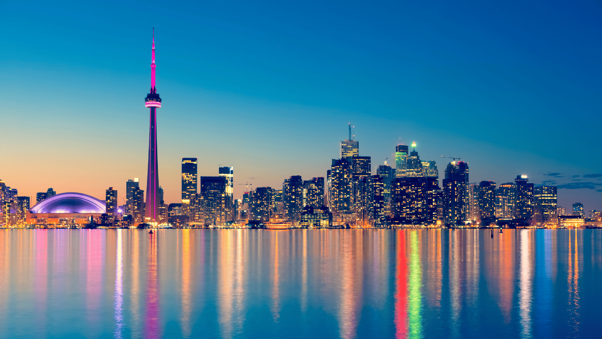 Toronto skyline at sunset with CN Tower reflecting over Lake Ontario