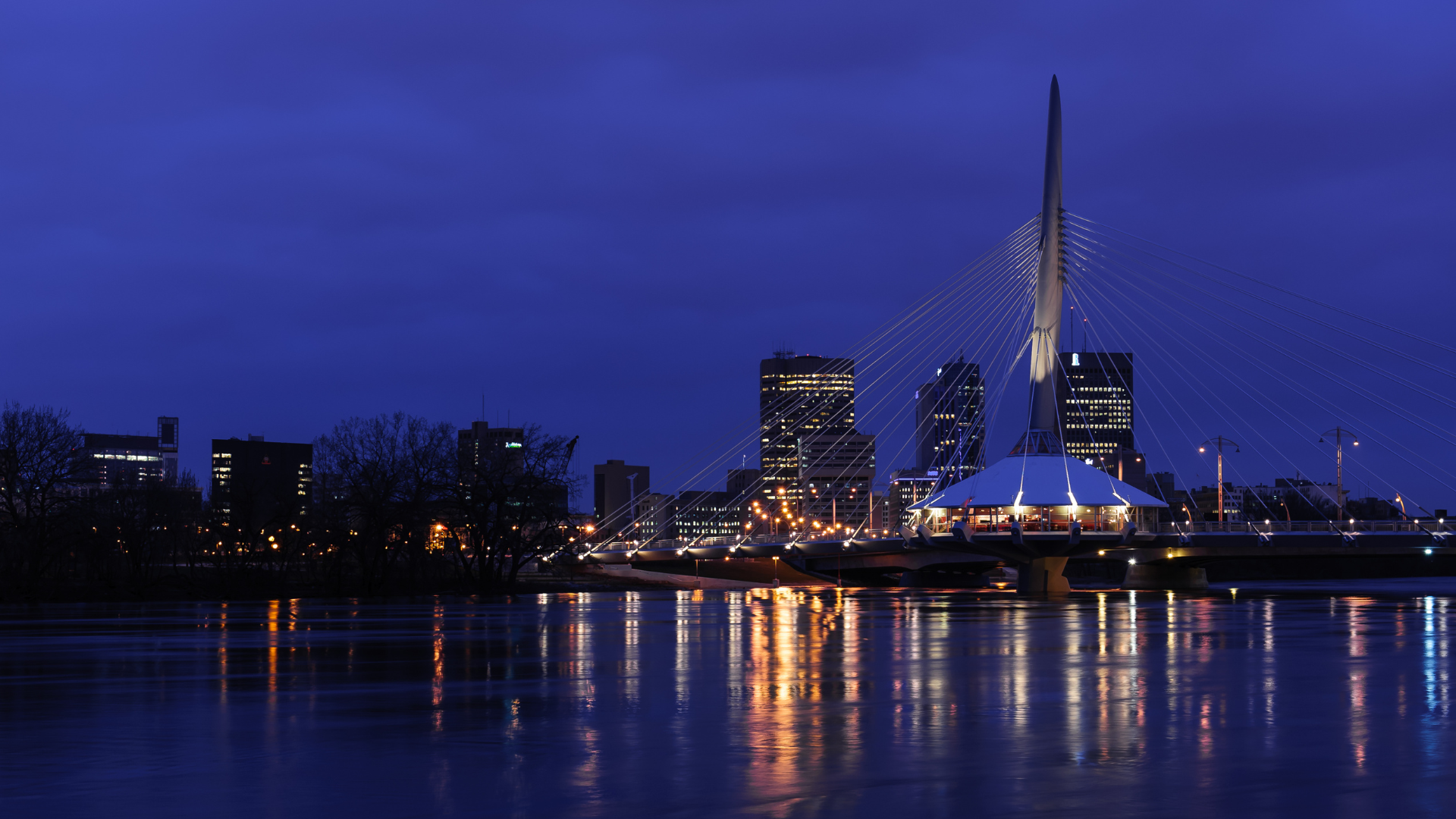Winnipeg downtown skyline at sunset overlooking the Esplanade Riel pedestrian bridge.