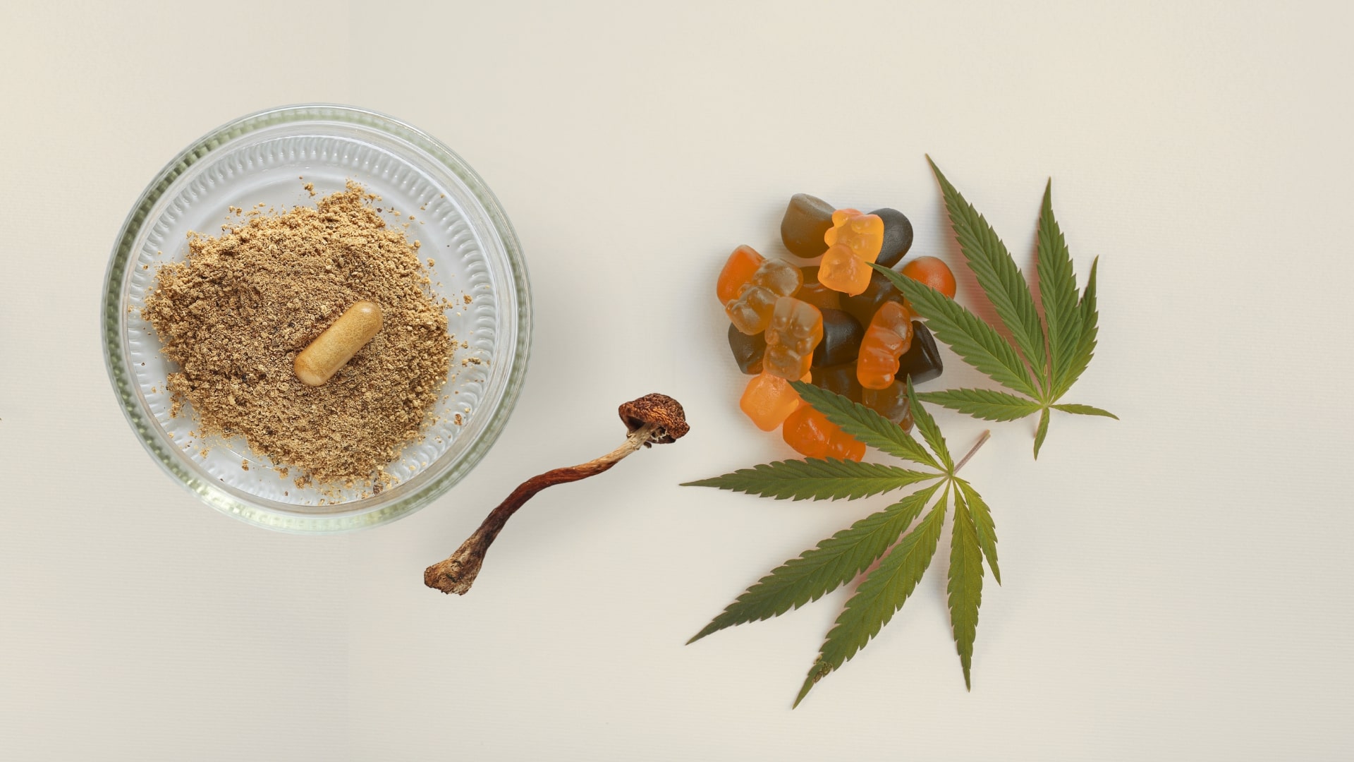 Psychedelic mushrooms, cannabis leaves, gummies, and capsule powder on neutral background.